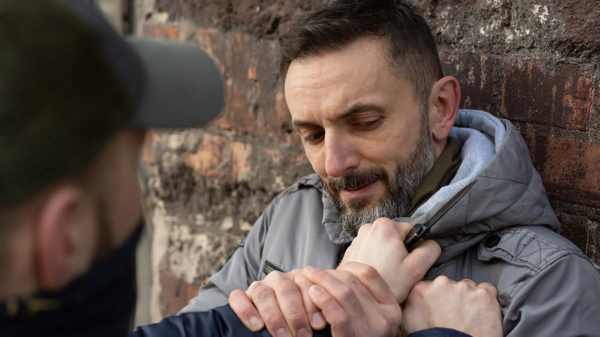 Zbliżenie ćwiczenia obrony przed nożem — obie ręce przyciskają dłoń napastnika trzymającą ostrze do ciała